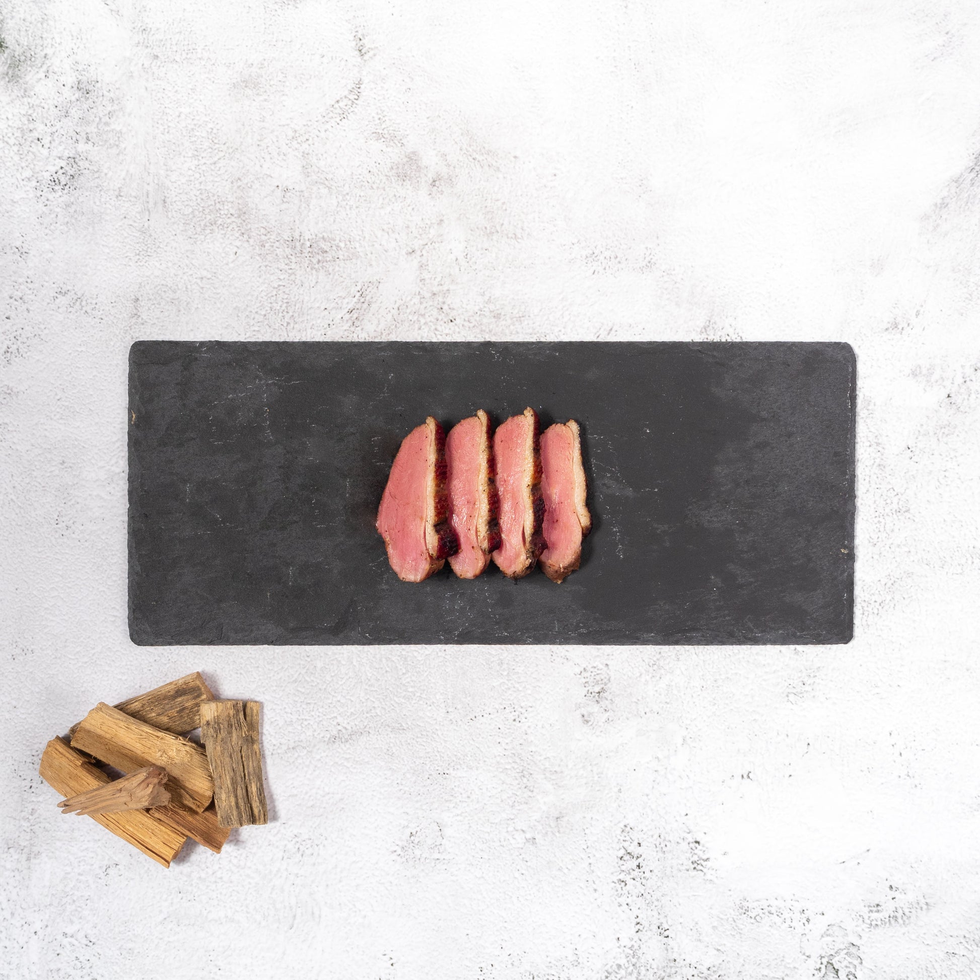 Applewood Smoked Duck on Stone Plate with Applewood Chips on the side.